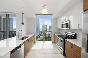 Miami apartment for rent - a kitchen with white countertops and wooden cabinets