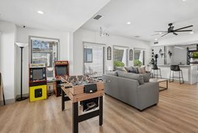 Albuquerque apartment for rent - A living room with a grey couch, a wooden coffee table, and a yellow arcade machine.