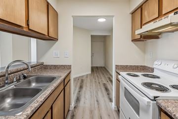 Albuquerque apartment for rent - A kitchen with wooden cabinets and a white stove top oven.