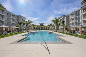 North Ft Myers apartment for rent - A large swimming pool in the middle of a resort surrounded by palm trees.