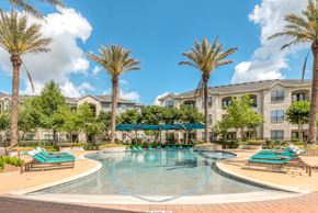 Richmond apartment for rent - A swimming pool surrounded by palm trees and lounge chairs.