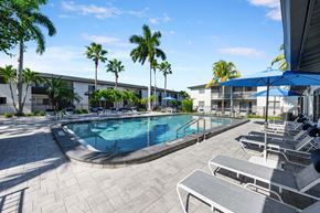 Fort Myers apartment for rent - a swimming pool with chairs and umbrellas in front of a building