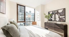 Atlanta apartment for rent - A bedroom with a large bed and a view of a cityscape through the window.