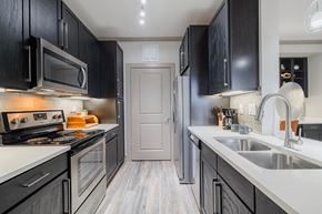 Houston apartment for rent - a kitchen with black cabinets and white counter tops and a sink