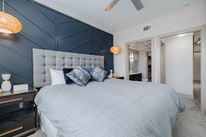 Houston apartment for rent - a bedroom with a large bed and a blue accent wall