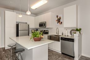 Orlando apartment for rent - A modern kitchen with white cabinets and stainless steel appliances.