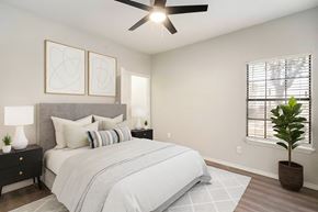 Fort Worth apartment for rent - A bedroom with a large bed, a ceiling fan, and two wall lamps.