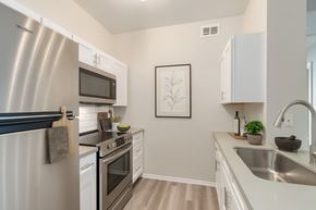 Fort Worth apartment for rent - A modern kitchen with a stainless steel refrigerator and white cabinets.