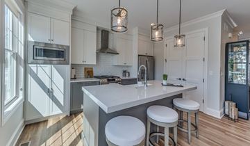 Elmhurst apartment for rent - A kitchen with white cabinets and a large island with three stools.