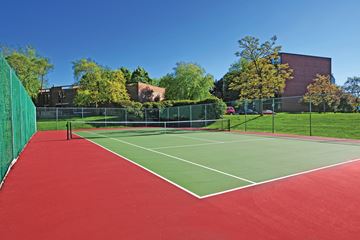 Elmhurst apartment for rent - A tennis court with a red surface and green fencing.