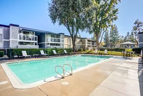 Sacramento apartment for rent - A swimming pool surrounded by trees and chairs in front of apartment buildings.