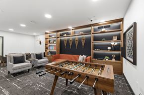 Jackson apartment for rent - A shiny wooden pool table is in the middle of a room with a black and white carpet.