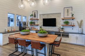Rockwall apartment for rent - A kitchen with a wooden table and chairs, a brick backsplash, and a TV above the island.
