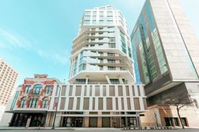 San Antonio apartment for rent - A modern building with a white facade stands in front of a red building and a glass building.