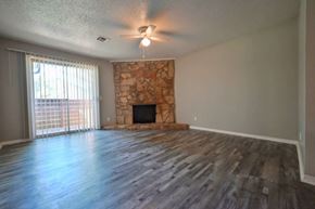 Oklahoma City apartment for rent - A room with a stone fireplace and wood flooring.