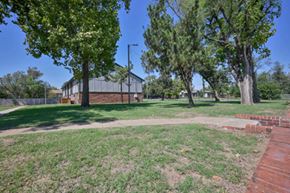 Oklahoma City apartment for rent - A park with a building in the background and a brick wall on the right.