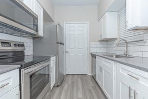 North Richland Hills apartment for rent - a kitchen with white cabinets and stainless steel appliances