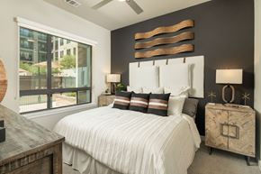Scottsdale apartment for rent - A bedroom with a large bed and a window overlooking a cityscape.
