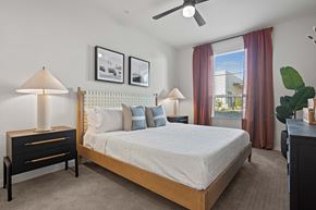 Mesa apartment for rent - A bedroom with a large bed, a nightstand with a lamp, and pictures on the wall.