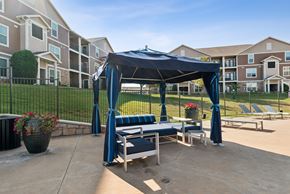 Oklahoma City apartment for rent - A gazebo with a blue canopy is situated in a courtyard with lounge chairs and potted plants.