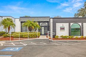 Tampa apartment for rent - a building with palm trees and a parking lot