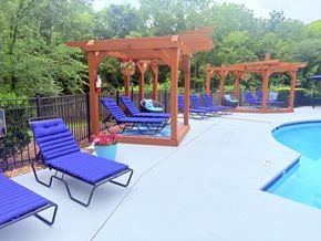 Concord apartment for rent - A poolside area with blue lounge chairs and a wooden pergola.