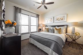 Houston apartment for rent - A bedroom with a large bed, a ceiling fan, and a side table with a lamp.