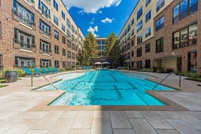 Houston apartment for rent - A long rectangular pool in the middle of a courtyard surrounded by buildings.