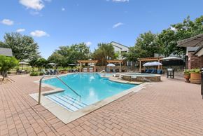 Austin apartment for rent - A pool surrounded by a brick patio with a blue sky in the background.