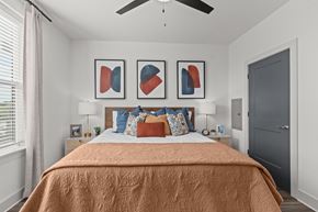 Huntersville townhouse for rent - A bedroom with a bed covered in an orange blanket and three framed artworks on the wall.