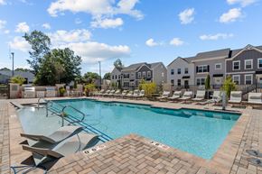 Huntersville townhouse for rent - A swimming pool surrounded by lounge chairs and apartment buildings.