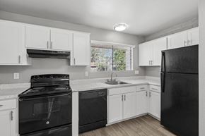 Tucson apartment for rent - A black refrigerator sits in a kitchen with white cabinets.