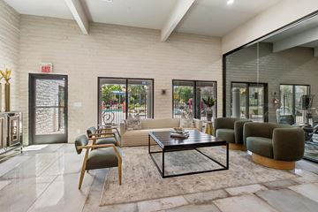 Tucson apartment for rent - A modern living room with a glass coffee table and a view of the backyard.