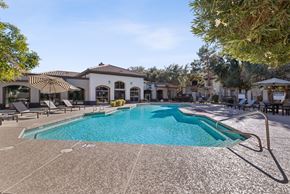 Phoenix apartment for rent - A large swimming pool in front of a building with a white facade and a striped awning.