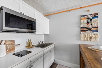 Mesa apartment for rent - A kitchen with white cabinets and a microwave above the stove.