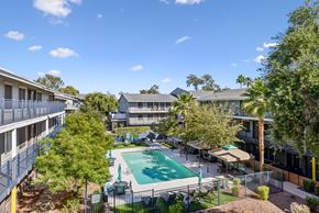 Phoenix apartment for rent - A pool surrounded by trees and apartment buildings.