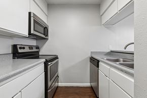Austin apartment for rent - A kitchen with white cabinets and a black stove top oven.
