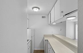 Dallas apartment for rent - A kitchen with white cabinets and a white fridge.
