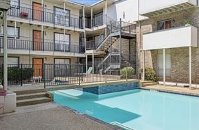 Dallas apartment for rent - A swimming pool in front of a building with a balcony.