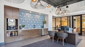 Fort Collins apartment for rent - A modern office space with a wooden desk and chairs, a TV, and a patterned backsplash.