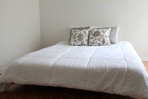 Dallas apartment for rent - a bedroom with a white comforter and pillows on a bed