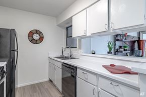 San Antonio apartment for rent - a kitchen with white cabinets and a sink and a refrigerator