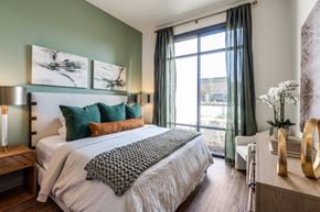 Mckinney apartment for rent - A bedroom with a large bed and a window with curtains.