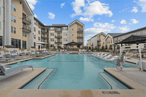 Buda apartment for rent - A large indoor swimming pool with lounge chairs and apartment buildings in the background.