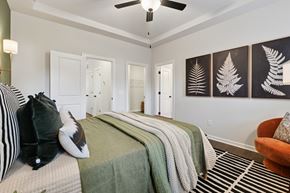 Charlotte townhouse for rent - A bedroom with a bed, pillows, a blanket, a chair, and a ceiling fan.