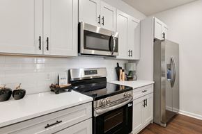 Charlotte townhouse for rent - A modern kitchen with white cabinets and stainless steel appliances.