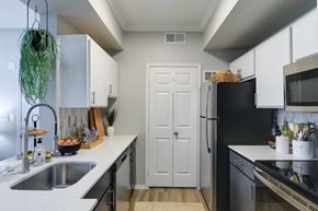 Plano apartment for rent - a kitchen with white cabinets and black and white appliances