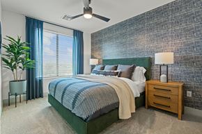 Phoenix apartment for rent - A bedroom with a bed, nightstand, and a plant.