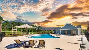 Myrtle Beach apartment for rent - A poolside area with chairs and a house in the background.
