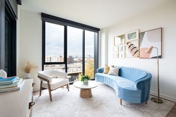 Washington apartment for rent - A blue couch sits in a living room with a large window overlooking the city.